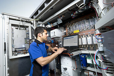 Ein JUWI-Techniker steht an einem Schaltkasten und überprüft die Verkabelung.