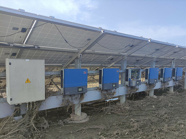 Eine Solarfarm mit Wechselrichtern, die nach einer Überschwemmung von Schutt bedeckt sind.