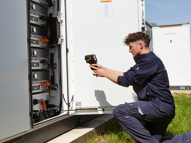 Mitarbeiter von JUWI führt eine Thermografie bei einem Batteriespeicher durch.