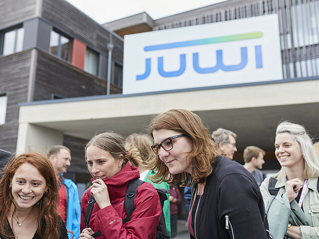 Eine Gruppe von JUWI-Mitarbeiter*innen stehen vor dem Eingang des Campus in Wörrstadt.