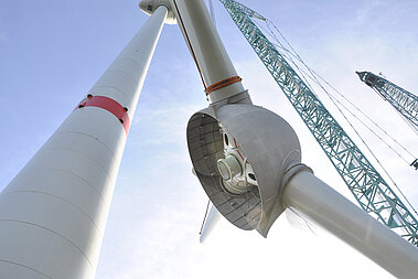 Ein Kran hebt die Flügel einer WEA an. 