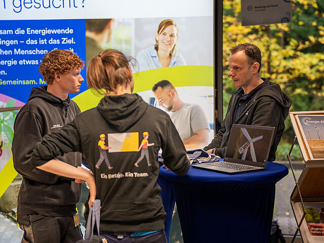 JUWI-Mitarbeitende an einem Messestand und beantwortet Fragen zu den Ausbildungsmöglichkeiten bei JUWI.