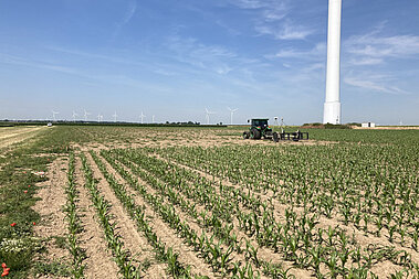 Ein Traktor auf der Suche nach Kampfmitteln. Im Hintergrund steht eine Windenergie-Anlage.