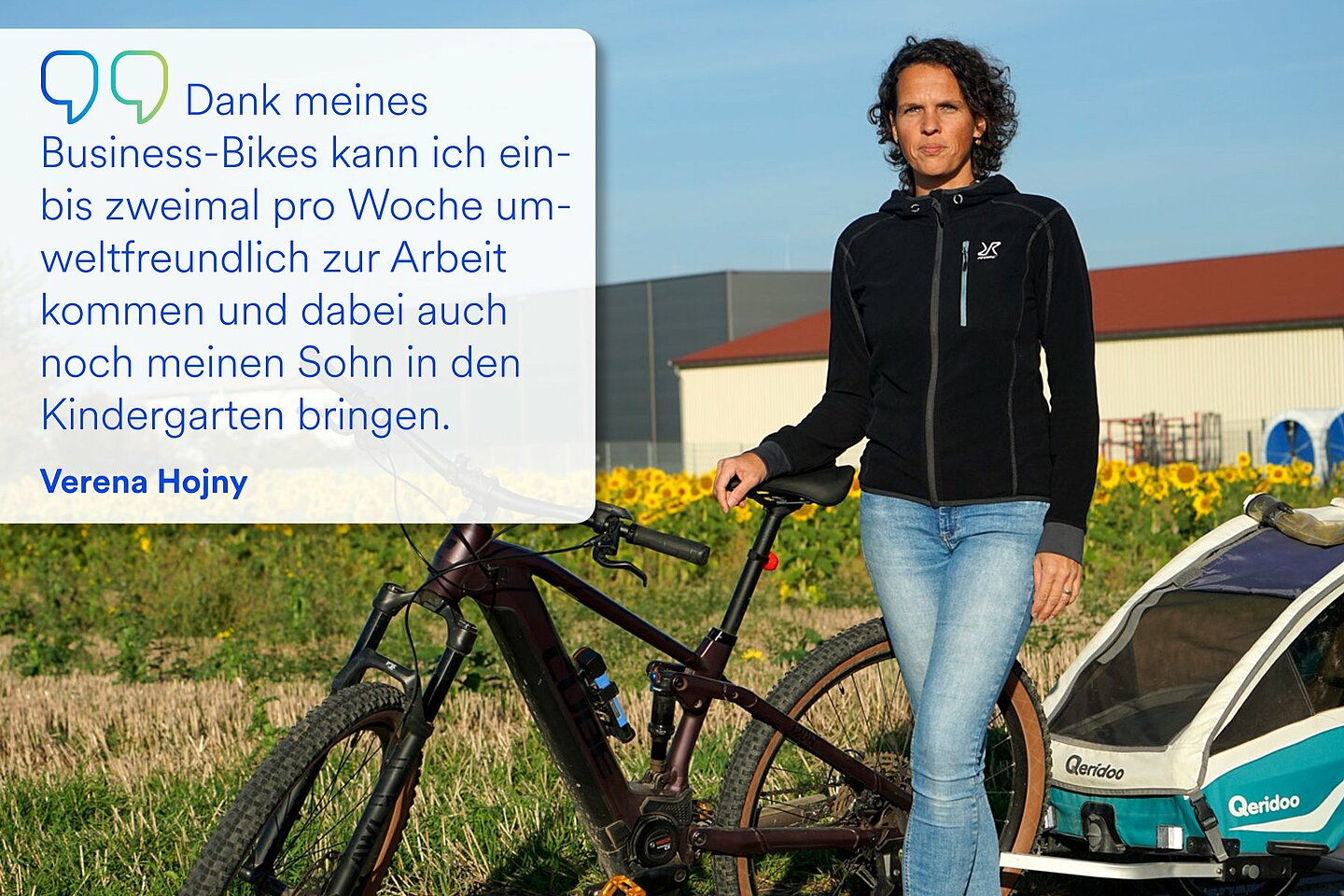 Verena Hojny steht neben ihrem Business-Bike, an dem ein Anhänger montiert ist. 