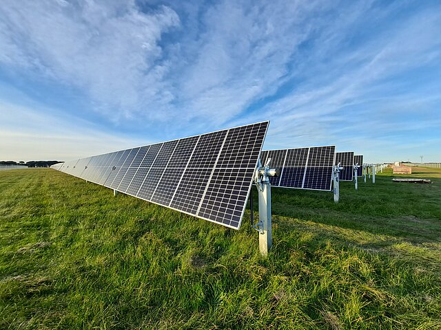 Eine Solar-Anlage im ersten Licht des Tages. Der Himmel ist mit Schleierwolken bedeckt.