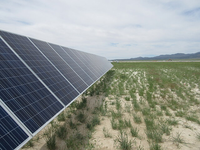 Photovoltaik-Module mitten in den Weiten Utahs. Am Horizont in der Ferne sind Berge erkennbar. 