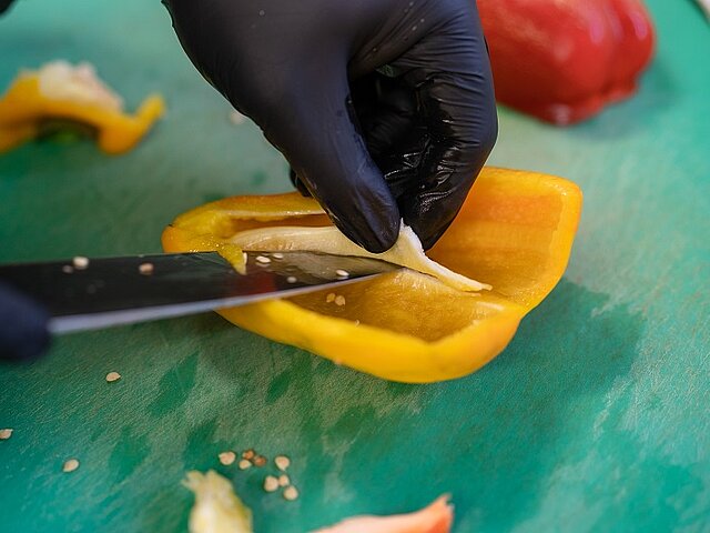 Nahaufnahme einer Paprika, die gerade geschnitten wird.