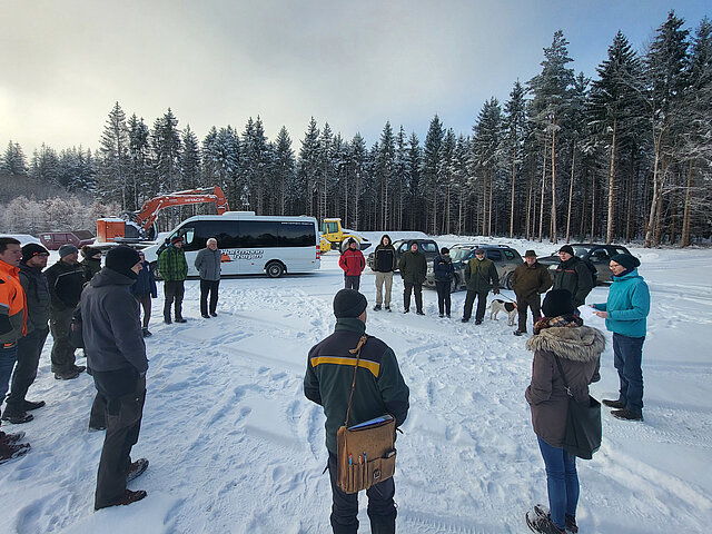 Mehrere Waldbesitzer stehen auf einer verschneiten Lichtung