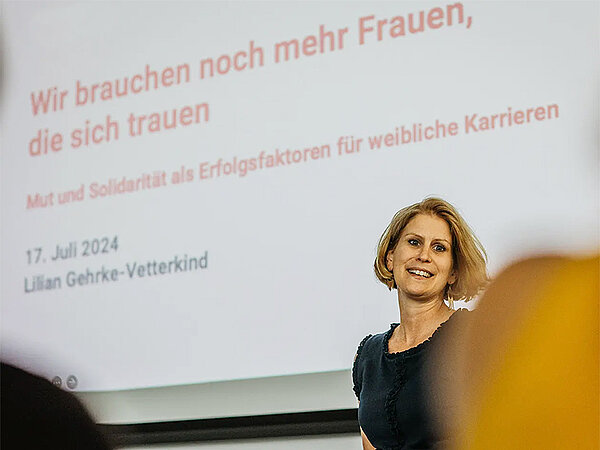Lilian Gehrke-Vetterkind steht auf einer Bühne und hält eine Präsentation.