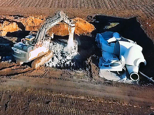 Ein Bagger trägt das Fundament einer WEA ab.