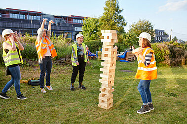 Mehrere JUWI-Mitarbeiter stehen bei einem Firmenevent vor einem großen Menga-Turm