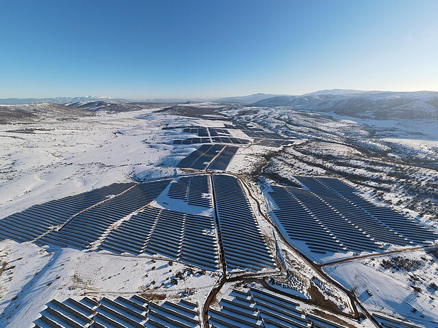 Der Solarpark Kozani aus der Vogelperspektive im Winter, Schnee bedeckt die Landschaft, der Himmel ist strahlend blau.