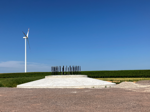Auf einem Ackerland steht eine bereits aufgebaute Windenergieanlage und das Fundament einer noch aufzubauenden Windenergieanlage.