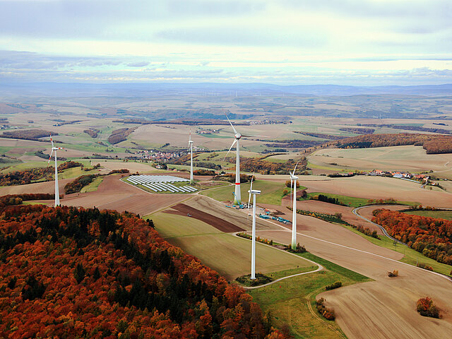 Mehrere Windenergie-Anlagen stehen in der herbstlichen Landschaft