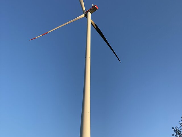 Eine Windkraftanlage ragt in den blauen Himmel hinein.
