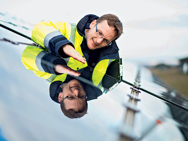 Ingo Klute steht vor einem PV-Modul und begutachtet es. 