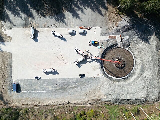 Auf einer Baustelle wird das Fundament einer Windenergie-Anlage mit Hilfe mehrere Betongmischfahrzeuge gegossen.