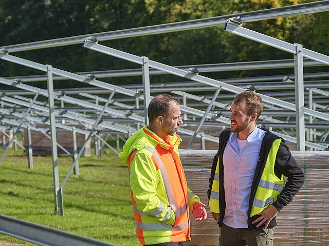 Zwei JUWI-Mitarbeiter stehen vor den Gestellen auf denen später Solarmodule befestigt werden.