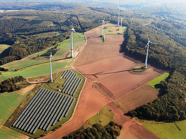 Ein Wind- und Solarpark stehen auf landwirtschaftlich genutzten Flächen an einem Waldrand