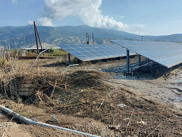 Solarkraftwerk nach Überschwemmung von Trümmern bedeckt, Berge im Hintergrund.