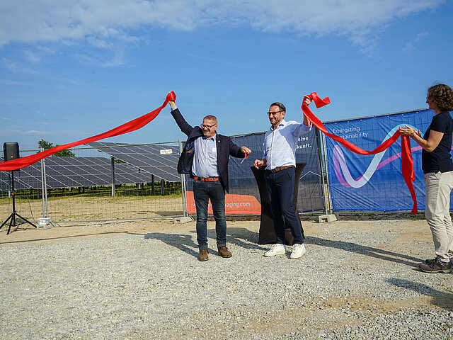 Die Geschäftsführer von JUWI und SPIES Packaging eröffnen symbolisch den Solarpark Gesmold. Sie zerschneiden ein rotes Band.